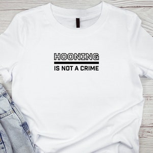 Puede incluir: Camiseta blanca con texto negro que dice "HOONING IS NOT A CRIME".