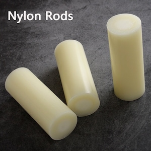 May include: Three off-white nylon rods, also known as dowels, are arranged on a grey textured surface. The text "Nylon Rods" is visible in the top left corner of the image.