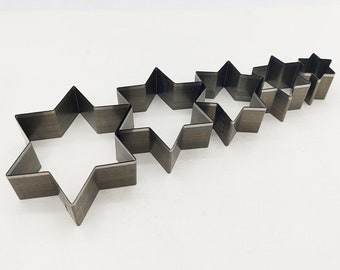 May include: Set of five metal star-shaped cookie cutters in various sizes. The cutters are arranged in a row from largest to smallest.