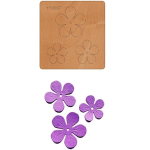 May include: A set of three purple paper flower die cuts. The die cuts are in the shape of a five-petal flower with a small circle in the centre. The die cuts are arranged in a triangular shape.