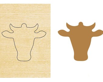May include: A wooden cutout of a cow head with a brown outline. The cutout is on a light brown wooden background.