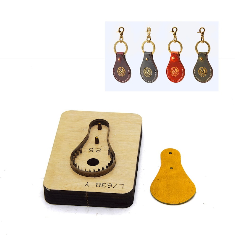 May include: A leather key fob with a metal key ring. The key fob is shaped like a teardrop and has a stitched edge. The key fob is brown, black, red, and green. The key fob has a metal stamp with a design on it. The key fob is shown next to a wooden die-cutting template with the number "L7938" and the text "2.5" on it. The die-cutting template is used to cut out the leather key fob.