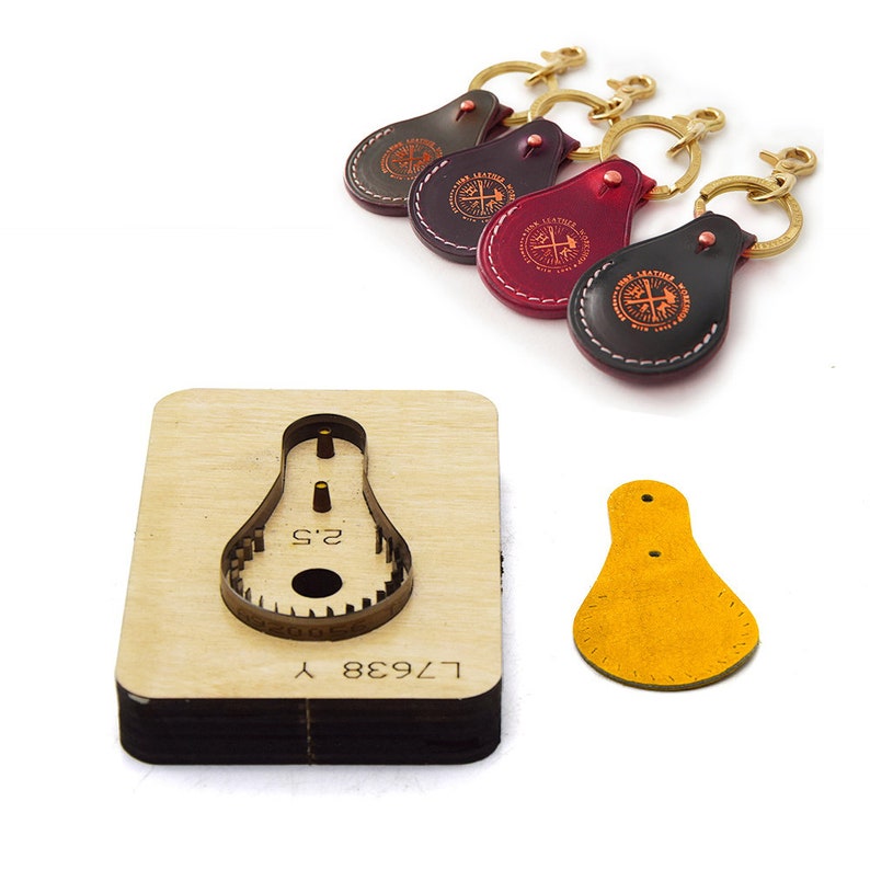 May include: Four leather keychains with a compass design and the text "Iron Leather Works" in a circle. The keychains are in different colors: brown, red, burgundy, and black. A wooden leather punch with the text "L7438 Y" and "2.5" is also shown. A yellow leather keychain is shown next to the punch.