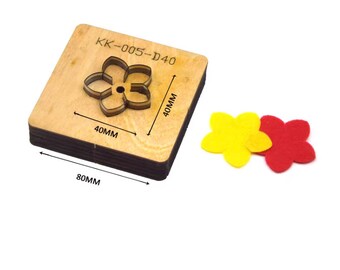 Puede incluir: Una herramienta de corte de madera para manualidades, con forma de flor. La matriz mide 80 mm x 40 mm. Dos flores de fieltro, una amarilla y otra roja, están junto a la matriz. El texto "KK-005-D40" está impreso en la matriz.