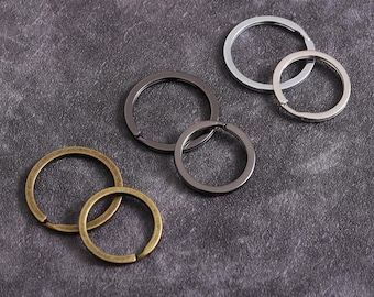 Può includere: Cinque portachiavi diversi in varie dimensioni e finiture. I portachiavi sono in metallo e sono di colore argento, nero e oro.