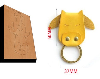 May include: A yellow leather keychain shaped like a cow with a gold metal ring. The keychain measures 50mm in height and 37mm in width.