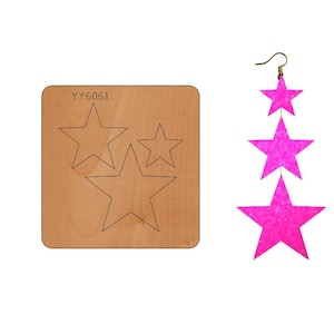 Puede incluir: Una plantilla de troquelado de madera con tres formas de estrella para hacer pendientes. La plantilla está etiquetada como "YY6061". Se muestra un par de pendientes de estrella de purpurina rosa.