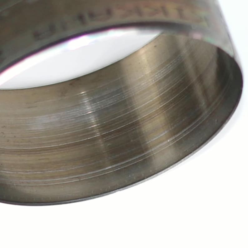 May include: A close-up of a silver metal ring with a smooth, brushed finish. The ring is round and has a slight curve to it.