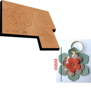 May include: A wooden craft die with three different flower designs. The die is labeled "XF 498". A green leather flower keychain is shown next to the die. The keychain is 60 mm in diameter.