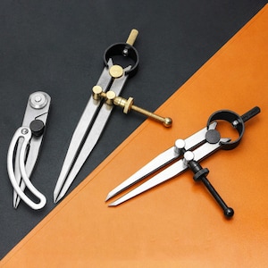 May include: Three metal calipers with sharp points and adjustable screws are displayed against a black and orange background. The calipers are silver, with brass and black accents. One is a small, curved design, while the others are larger, with straight legs.