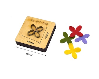 Puede incluir: Una plantilla de troquelado de madera con el texto "KK-017-D40" y medidas de 40 mm x 80 mm. La plantilla está diseñada para cortar una forma de flor de cuatro pétalos. Se muestran cuatro flores de fieltro en rojo, verde, morado y amarillo junto a la plantilla.