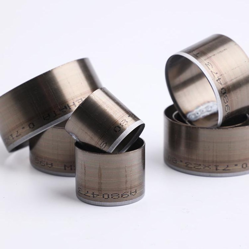 May include: A set of five metal rings with different sizes. The rings are silver in color and have markings on the inside and outside. The markings include numbers and letters.