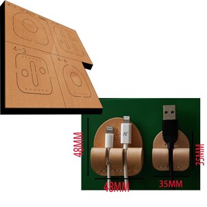 Könnte beinhalten: Ein Leder-Kabelorganizer mit drei Schlitzen für Ladekabel. Der Organizer ist 48 mm breit und 35 mm hoch. Der Organizer ist aus braunem Leder gefertigt und hat eine hellbraune Naht an den Rändern.