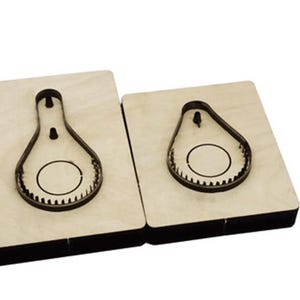 May include: Two wooden cutting dies, one larger than the other, with a pear-shaped cutout. The cutouts have a circle inside.