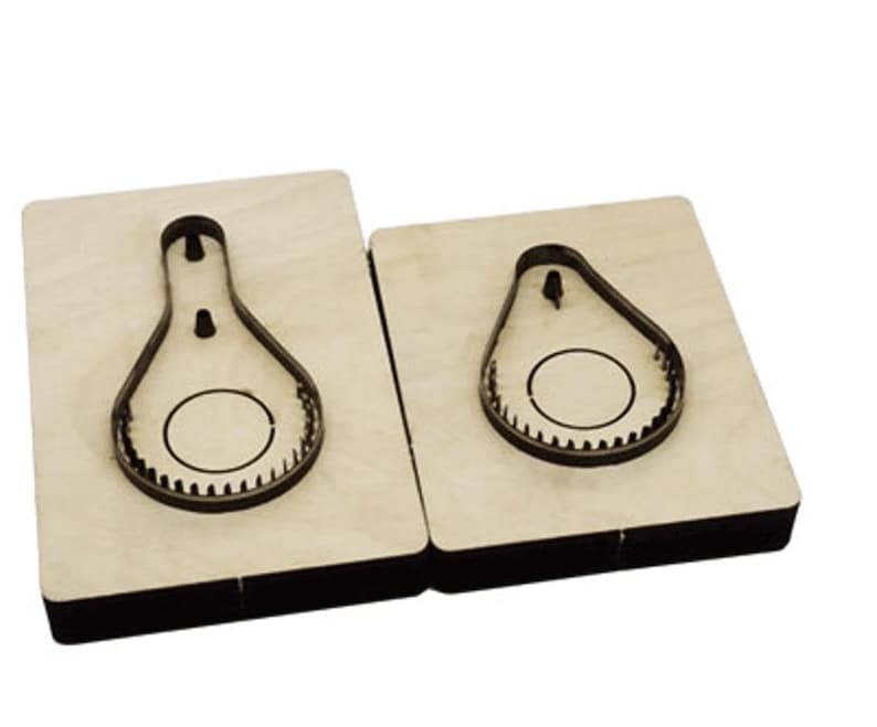 May include: Two wooden cutting dies, one larger than the other, with a pear-shaped cutout. The cutouts have a circle inside.