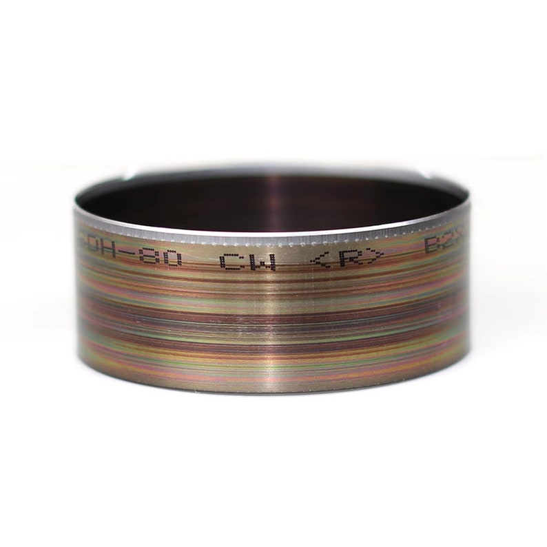May include: A silver metal ring with a textured surface and black markings that read "OH-80 CW <RX> B".