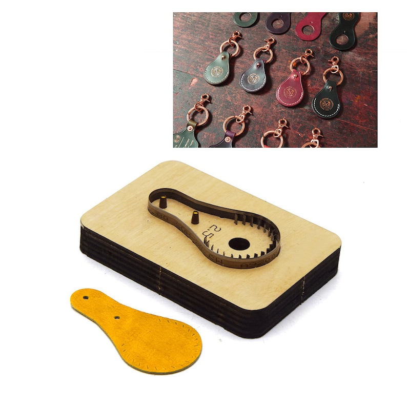 May include: A wooden leather craft punch tool with a cut-out shape of a teardrop with two holes. A yellow leather piece is cut out using the punch tool.