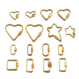 May include: A collection of gold-colored carabiner clips in various shapes, including hearts, stars, ovals, and squares. Each clip features a screw-lock mechanism for secure closure. The shapes vary in size and design, offering a range of options.
