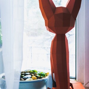 Peut inclure: Une sculpture g&eacute;om&eacute;trique en papier repr&eacute;sentant un renard, dans des tons orange et marron, est pos&eacute;e sur un rebord de fen&ecirc;tre. Le renard est &agrave; c&ocirc;t&eacute; d'un petit bol avec des pierres et de la verdure.