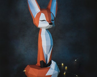 May include: A papercraft fox sculpture in shades of orange, white, and gray, with closed eyes, sitting upright. The fox has a geometric, polygonal design. The background is a dark, textured surface, with a string of small, warm-toned lights.