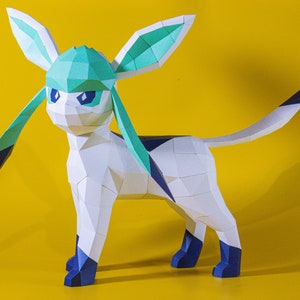 Może przedstawiać: Papierowa figurka Glaceona, postaci z Pokémonów, na żółtym tle. Figurka jest biała z jasnoniebieskimi, granatowymi i czarnymi akcentami. Projekt charakteryzuje się geometrycznymi kształtami.