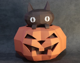 May include: A geometric papercraft Halloween decoration featuring a jack-o'-lantern with a carved face and a black cat perched on top. The pumpkin is orange, and the cat has white eyes.
