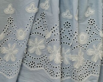 May include: Light blue fabric with white eyelet embroidery and floral designs. The fabric has a delicate and feminine look.