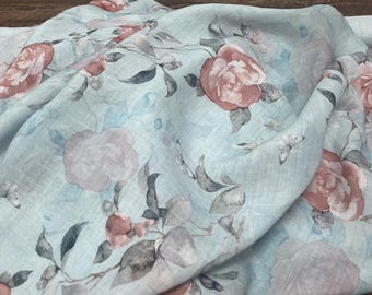May include: A light blue linen fabric with a floral pattern featuring pink and red roses and butterflies. The fabric has a soft, textured feel.