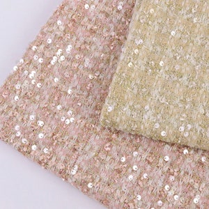 Könnte beinhalten: Zwei Stoffmuster mit Tweed-Struktur und Pailletten. Ein Muster ist rosa und das andere beige.