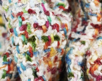 Puede incluir: Primer plano de una tela texturizada y colorida con fondo blanco. La tela está hecha de una variedad de hilos de diferentes colores, creando un patrón único e interesante.