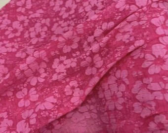May include: Pink fabric with a white floral pattern. The fabric is sheer and has a textured surface.