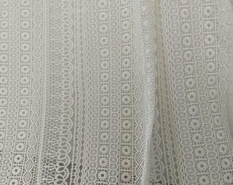 May include: White lace fabric with a delicate pattern of circles and ovals. The fabric has a soft, airy feel and is perfect for crafting projects.
