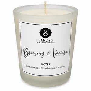 May include: A scented candle in a frosted glass jar with a white label featuring the text SANDYS HOMEMADE CANDLES, Blueberry & Vanilla, and NOTES Blueberries • Strawberries • Vanilla. The candle has a single centred cotton wick.