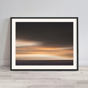May include: Abstract art print of a blurred sunset over a body of water. The colors are mostly shades of orange, yellow, and brown.