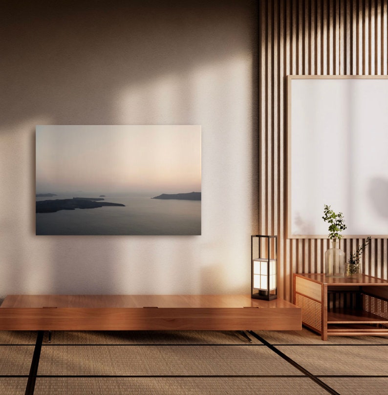 May include: A rectangular wall art print featuring a landscape of dark islands surrounded by a calm sea under a soft, hazy sky. The print is mounted on a plain wall above a low, horizontal wooden console table with a clean, flat surface.