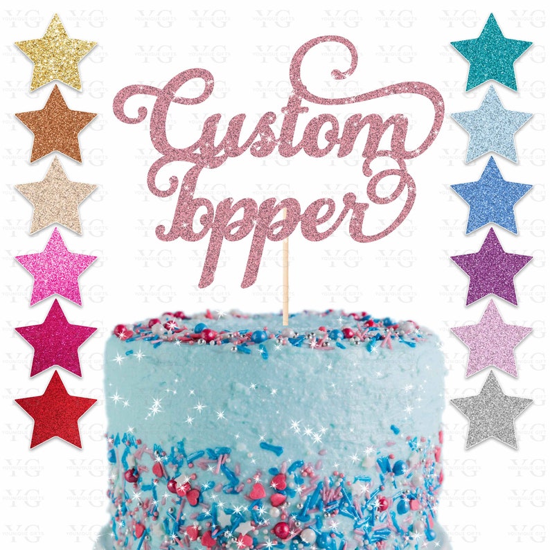 K&ouml;nnte beinhalten: Rosa glitzernder Tortendekor mit den Worten "Custom Topper" auf einem blau gefrosteten Kuchen mit Streuseln. Der Tortendekor ist auf einem Holzstiel.