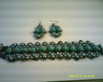 May include: A turquoise and silver beaded bracelet and matching earrings. The bracelet is made with small silver beads and larger turquoise beads. The earrings are also made with silver and turquoise beads.