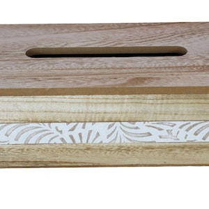 May include: A rectangular wooden tissue box cover featuring a natural light brown wood grain finish on the top and bottom sections, with a central horizontal band displaying a white repeating leaf or fan-shaped pattern across the front face.