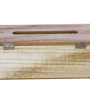 May include: A rectangular light brown wooden tissue box cover with a visible natural wood grain pattern. The top features a centered elongated oval opening for dispensing tissues, and the front panel is attached with two small silver metal hinges.