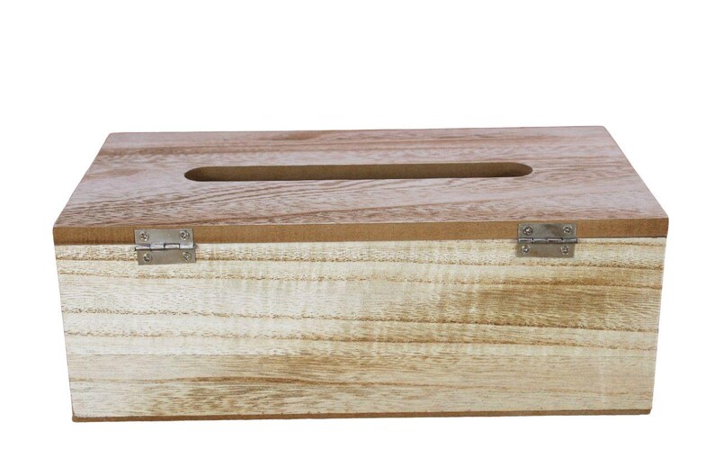 May include: A rectangular light brown wooden tissue box cover with a visible natural wood grain pattern. The top features a centered elongated oval opening for dispensing tissues, and the front panel is attached with two small silver metal hinges.