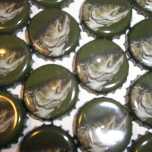 May include: A collection of green bottle caps with a fish design. Each cap features a detailed illustration of a fish, set against a diagonal dark stripe. The caps are arranged closely together, creating a pattern.