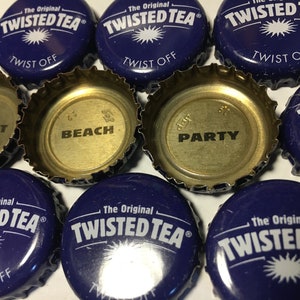 May include: Close-up of nine purple bottle caps with the words "Twisted Tea" and "Twist Off" printed on them. The inside of the caps are gold and have the words "Great", "Beach", and "Party" printed on them.