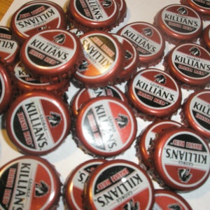 May include: A collection of red and white bottle tops from Killian's Irish Red beer. The tops feature the brand's logo and text.
