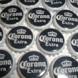 Może przedstawiać: Kolekcja czarno-białych zakrętek od butelek Corona Extra. Zakrętki są ułożone w losowym wzorze. Zakrętki są wykonane z metalu i mają srebrne wykończenie.