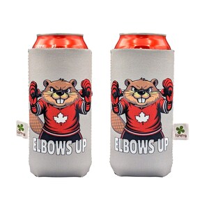 May include: Two grey can coolers featuring a cartoon beaver in a red hockey jersey with a white maple leaf. The beaver has its arms raised, wearing red boxing gloves. The text "ELBOWS UP" is below the beaver.