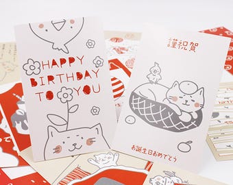 May include: A collection of greeting cards featuring cat and bird illustrations. One card reads "Happy Birthday To You" in red. Another card has Japanese text and a cat in a basket. Other cards have red and white patterns.