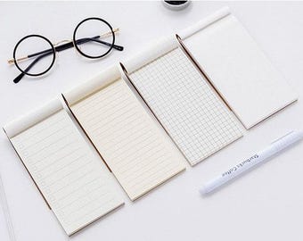 May include: Five small white memo pads with different lined patterns, including blank, lined, and gridded paper. A white pen with black text is also included.