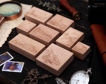 May include: A set of eight wooden stamps featuring various cityscapes. The stamps are rectangular and have a light brown colour. The designs are engraved into the wood and show detailed cityscapes with buildings, trees, and other architectural elements.