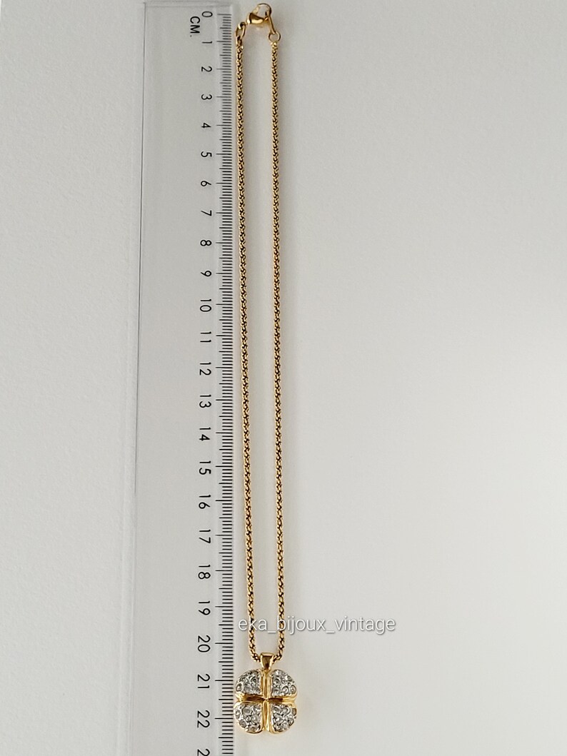 K&ouml;nnte beinhalten: Eine goldene Kettenkette mit einem vierbl&auml;ttrigen Kleeblatt-Anh&auml;nger, der mit klaren Strasssteinen besetzt ist. Die Kette ist 22 cm lang.
