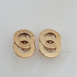 Puede incluir: Pendientes de metal dorado con las palabras "CELINE PARIS" grabadas en cada pendiente.